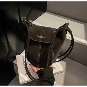 Detail of suede bucket bag featuring contrast white stitching and gold brand logo