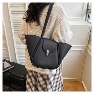Detail of black pebbled leather shoulder bag with side wing design and metal buckle