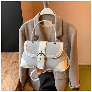 Close-up of grey suede shoulder bag with white trim and large silver buckle detail