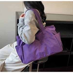 Detail of a large purple checkered tote bag featuring a durable woven texture and side pockets