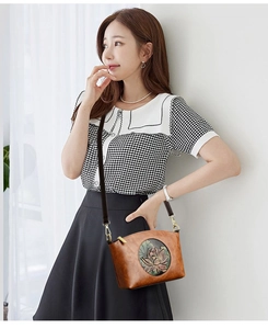 Detail of vintage lotus embossed brown leather crossbody bag worn by a female model