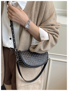 Close-up of black leather half-moon crossbody bag with silver rivet stud detailing