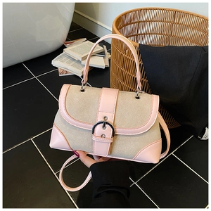 Detail view of pink and beige patchwork handbag with silver horseshoe buckle on marble floor
