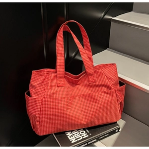 Macro detail of the red checkered tote bag with side pockets on a modern staircase