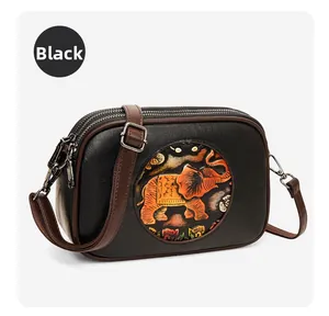 Détail du sac bandoulière noir avec relief d'éléphant coloré et bandoulière marron