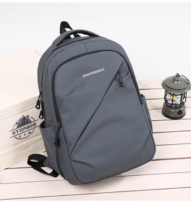 Détail du sac à dos gris en nylon imperméable avec poche zippée sur surface blanche