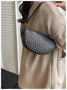 Detail of black crescent shoulder bag featuring silver rivets on a female model