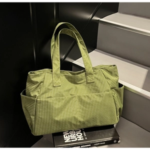 Detail of green plaid canvas tote bag showing front pocket and woven fabric texture
