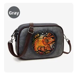 Détail d'un sac bandoulière gris rétro avec emblème éléphant en relief et double zip