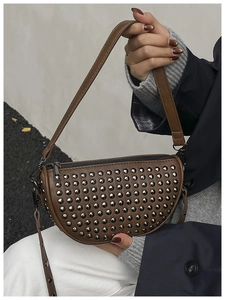 Close-up of a dark brown crescent bag featuring matte PU leather and metal rivet details