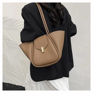 Detail shot of brown lychee leather texture and golden metal buckle on shoulder bag