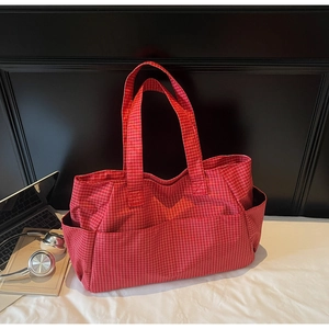 Detail of red checkered canvas tote bag with side pockets on an office desk setting