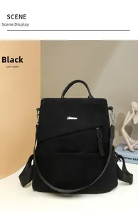 Detail view of black corduroy backpack with leather handle and rectangular metal accent