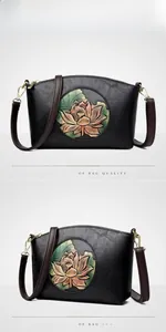 Detail view of vintage lotus flower relief on black leather crossbody bag with gold hardware