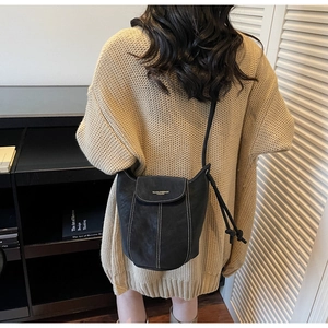 Detail of black suede bucket bag with contrast white stitching and knot handle