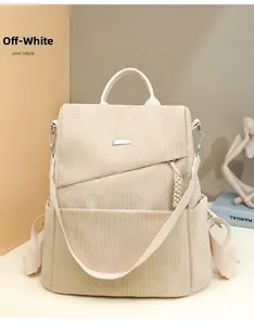 Detail of creamy white corduroy backpack with metallic magnetic buckle and woven pendant