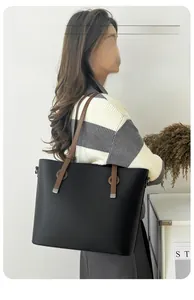 Détail du sac cabas en cuir grainé noir avec anses marrons porté par un mannequin chic