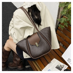 Detail of a brown woven tote bag with a gold metal clasp and long leather straps