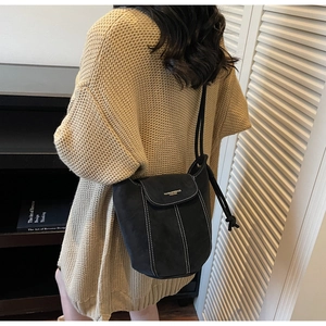 Detail of black suede bucket bag with white contrast stitching and drawstring closure