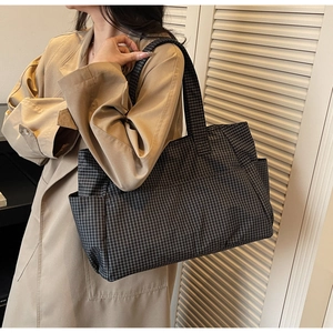 Detail of checkered tote bag showing wide shoulder strap and side pocket for daily use