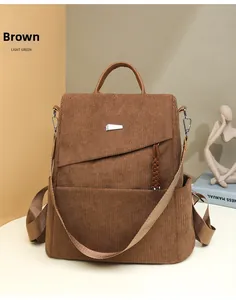 Detailed view of brown corduroy backpack showing leather handle and silver metal accents