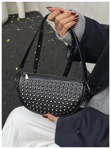 Detail of black crescent moon bag featuring dense silver rivets and adjustable strap