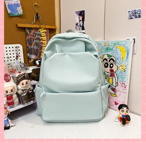 Detail view of mint green minimalist backpack showing front zipper pocket and side sleeve