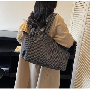 Detail view of a large checkered tote bag showing the textured fabric and shoulder strap