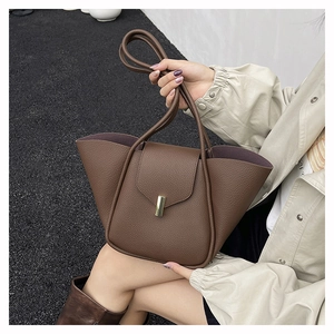 Close-up of caramel leather tote bag with woven texture and gold metal buckle