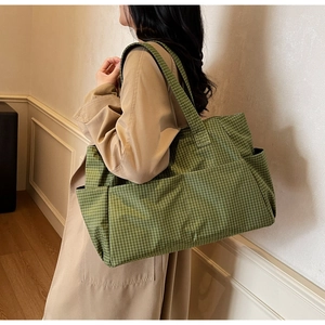 Detail of spacious light green checkered tote bag showing side pocket and canvas texture