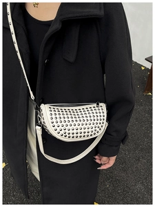 Detail of white saddle bag with metallic rivets on black wool coat model