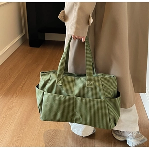 Detail of green plaid tote bag showing symmetric front pockets and woven canvas texture