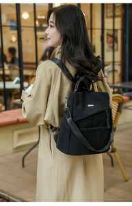 Detail of black corduroy backpack with silver buckle on khaki coat background