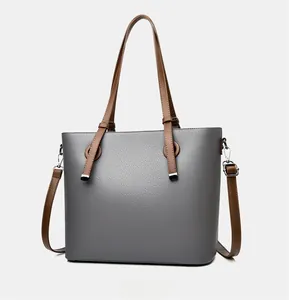 Vue détaillée du sac cabas en cuir grainé gris avec des anses marron et anneaux en métal