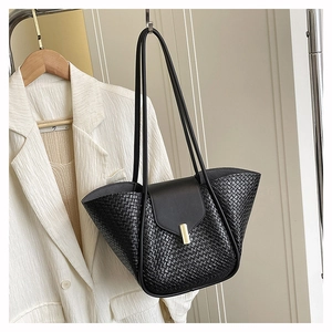 Close-up of black woven texture and gold metal buckle on elegant women's tote bag