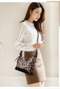 Dettaglio della borsa leopardata con base in pelle nera e ciondolo a nappa decorativo