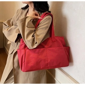 Detail of red plaid canvas tote bag with large front pocket and spacious storage design