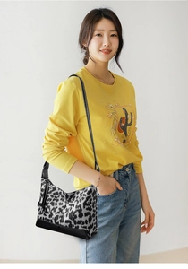 Foto lifestyle di una borsa a mezzaluna con stampa leopardata e outfit casual