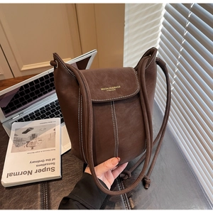 Detail of dark brown leather bucket bag with white contrast stitching and rope shoulder strap