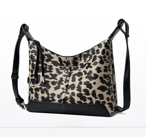 Vista laterale della borsa hobo leopardata con finiture in pelle nera e nappe decorative