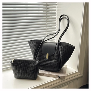 Detail of black woven texture tote bag and small clutch with elegant gold hardware
