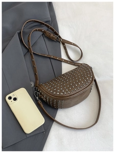 Brown rivet studded half-moon crossbody bag shown next to a smartphone for size reference