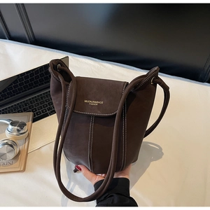 Close-up of dark brown suede bucket bag with white contrast stitching and gold lettering