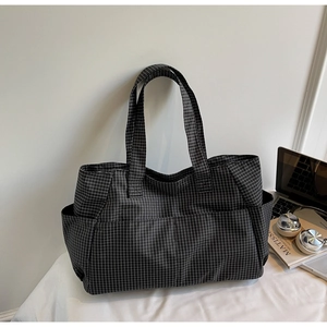 Detail of checkered tote bag with side pockets showing large capacity for laptop