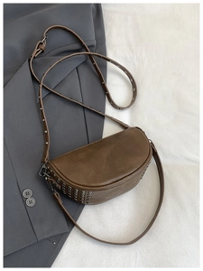 Close-up of brown saddle bag featuring vintage leather texture and silver metal rivets