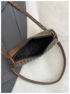 Detail of vintage brown cylinder bag with rivets, interior lining and dual straps