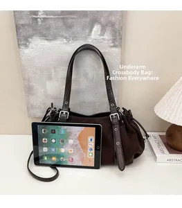 Detail of dark brown ruched shoulder bag with wide strap and silver metal buckle hardware