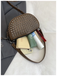 Detail of studded brown shell bag interior showing storage space for phone and wallet