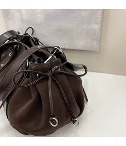Detail of dark brown leather bucket bag with silver metal hooks and drawstring rings