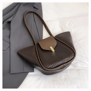 Detail of dark brown woven handbag featuring textured lattice and gold metal clasp